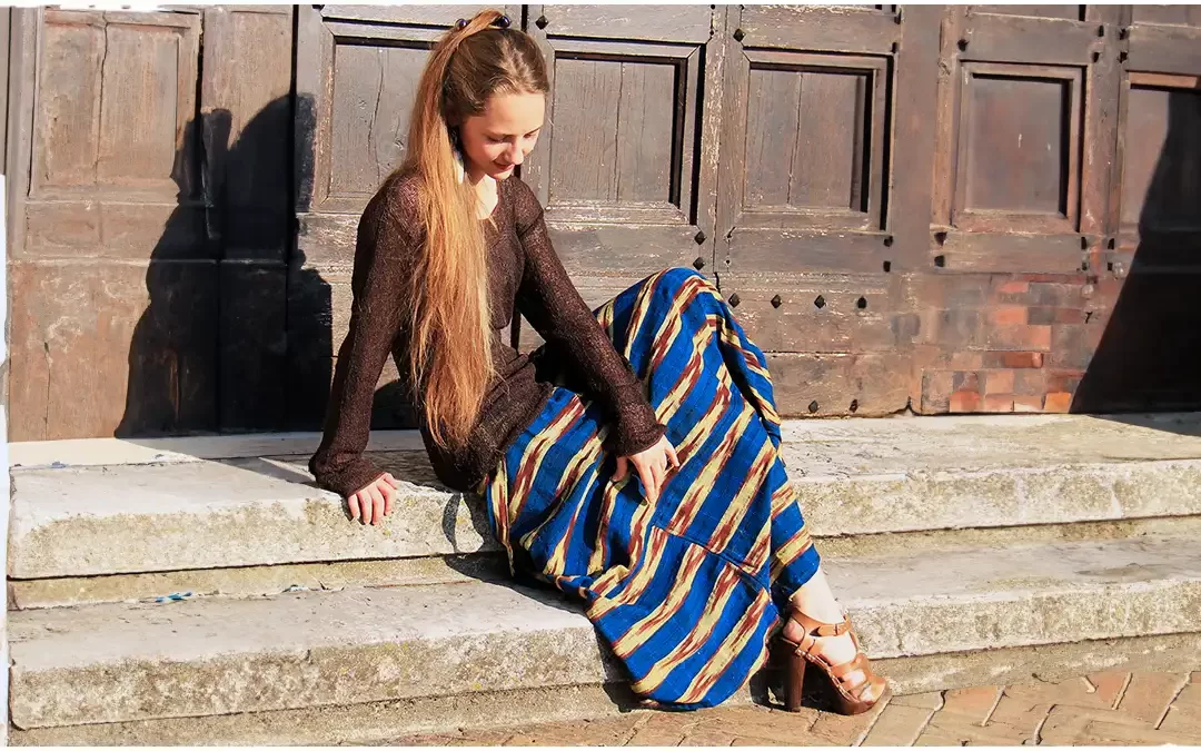 a beautiful blonde girl sitting on the stone steps of an ancient church