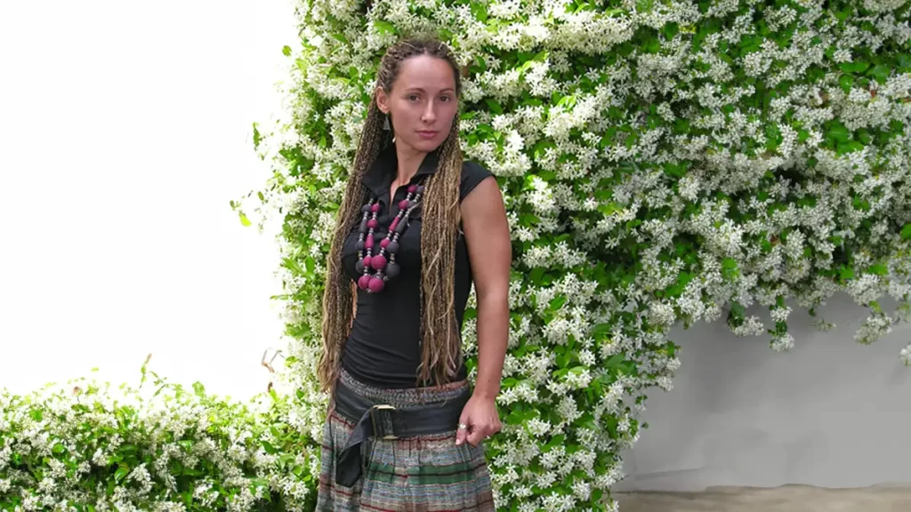 bohemian skirt young woman with boho hippie clothing, standing in front of a large blooming jasmine plant