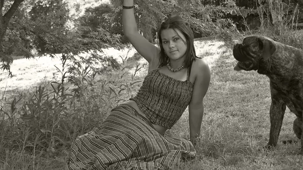 boho fashion girl sitting in a meadow with a large dog next to her