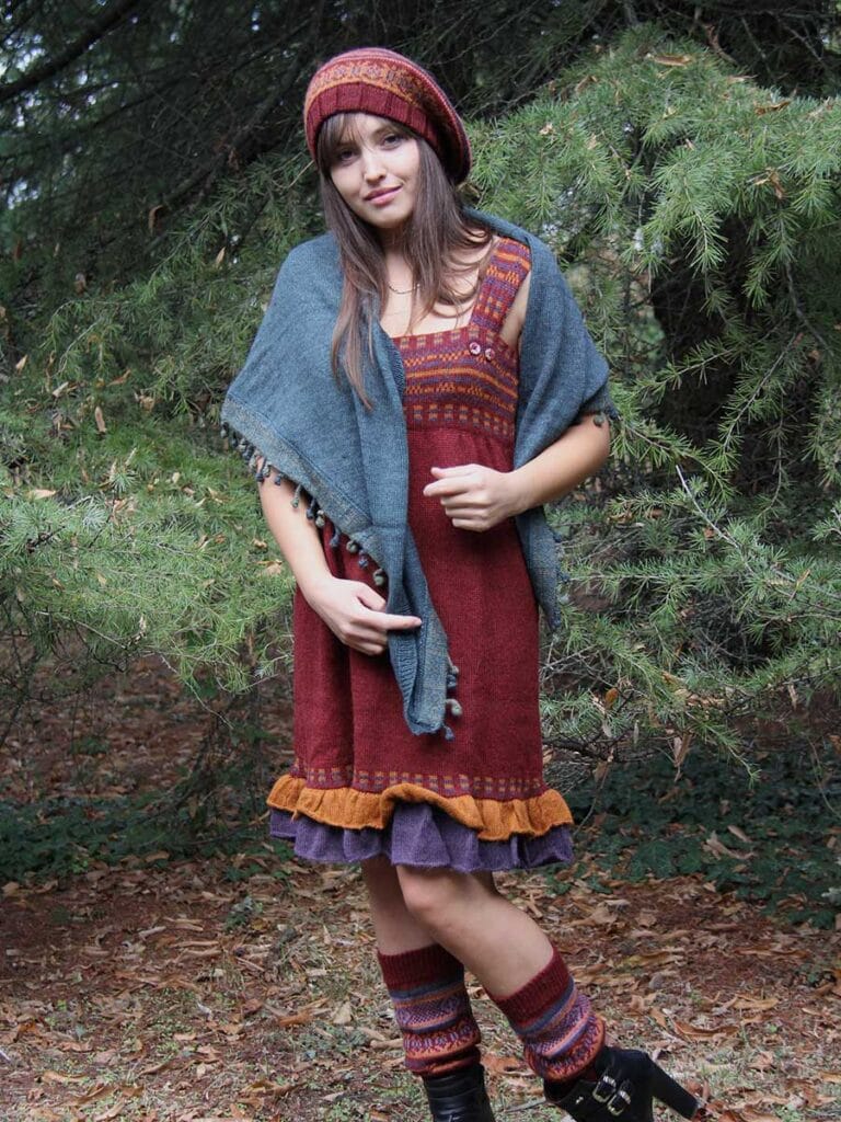 Women's look knitted dress - A woman poses in a sleeveless red knitted dress under a large fir tree